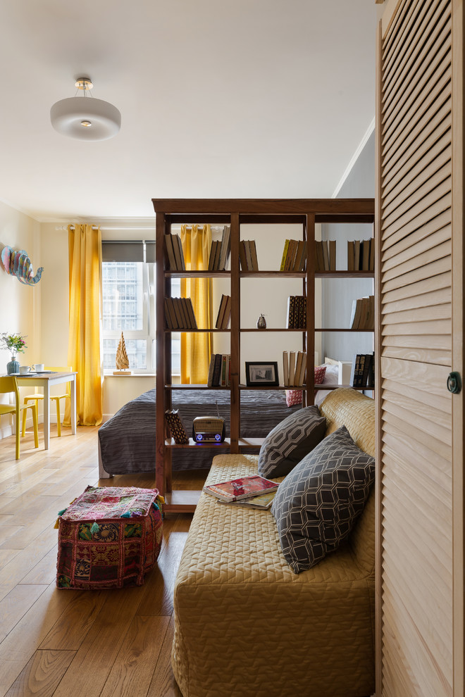 Foto på ett litet eklektiskt loftrum, med ett bibliotek, beige väggar, laminatgolv och en väggmonterad TV