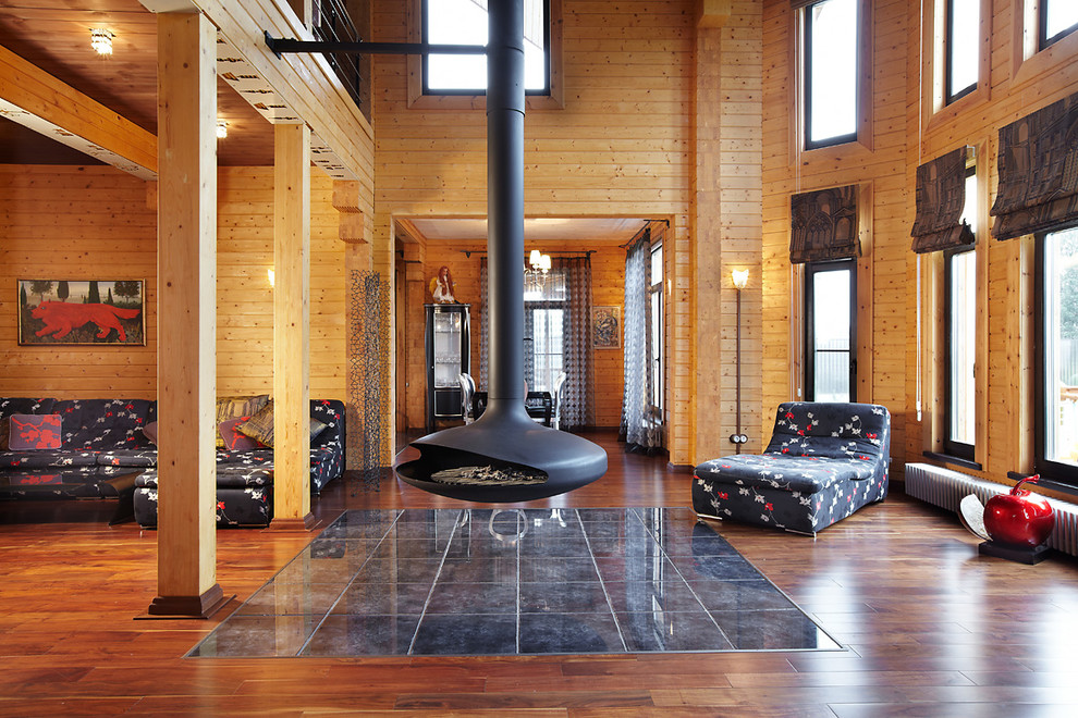 На фото: гостиная комната среднего размера в современном стиле с бежевыми стенами, подвесным камином, коричневым полом и тюлем на окнах с