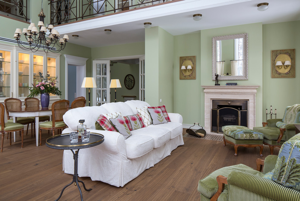 Пример оригинального дизайна: парадная гостиная комната в классическом стиле с зелеными стенами, паркетным полом среднего тона, стандартным камином и фасадом камина из камня
