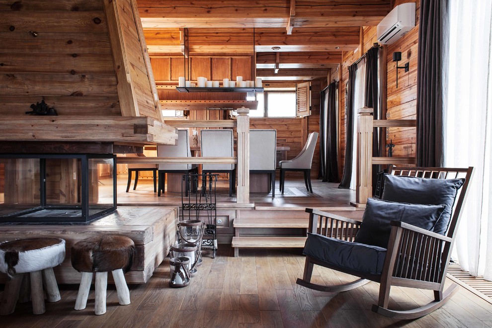 Diseño de salón para visitas abierto rural con paredes marrones, suelo de madera en tonos medios, chimenea de doble cara y marco de chimenea de madera