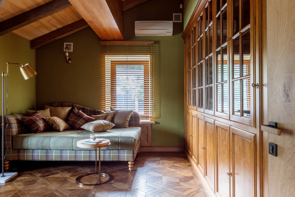 Идея дизайна: гостиная комната:: освещение в стиле кантри с с книжными шкафами и полками, зелеными стенами, паркетным полом среднего тона и коричневым полом