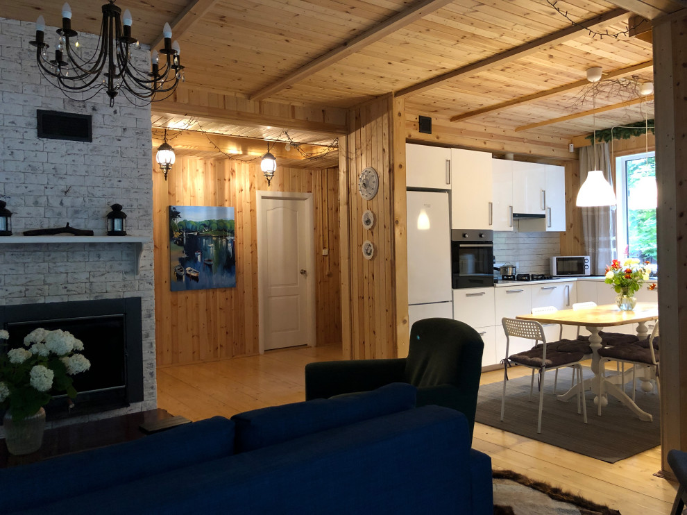 Foto di un soggiorno aperto e di medie dimensioni con pavimento in legno verniciato, camino classico, cornice del camino piastrellata e TV a parete