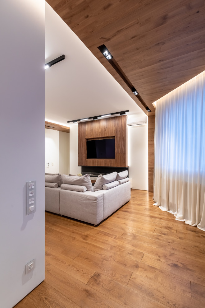 На фото: гостиная комната в стиле неоклассика (современная классика) с коричневыми стенами, темным паркетным полом, горизонтальным камином, мультимедийным центром и коричневым полом