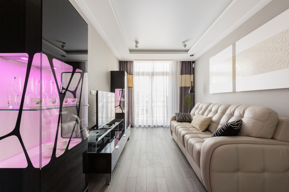 Стильный дизайн: гостиная комната среднего размера в современном стиле с темным паркетным полом, отдельно стоящим телевизором, обоями на стенах, серыми стенами, коричневым полом и многоуровневым потолком - последний тренд