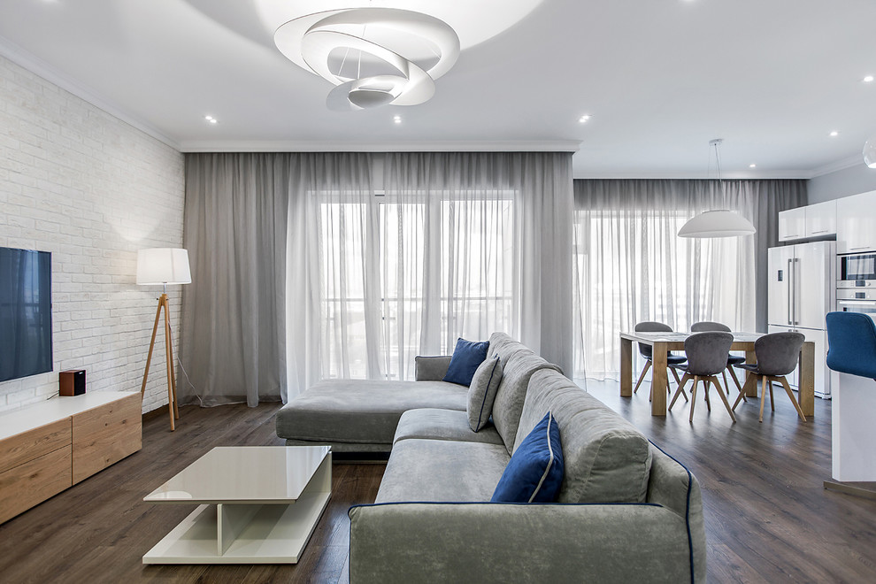 Стильный дизайн: парадная, открытая гостиная комната в скандинавском стиле с белыми стенами, темным паркетным полом и телевизором на стене - последний тренд