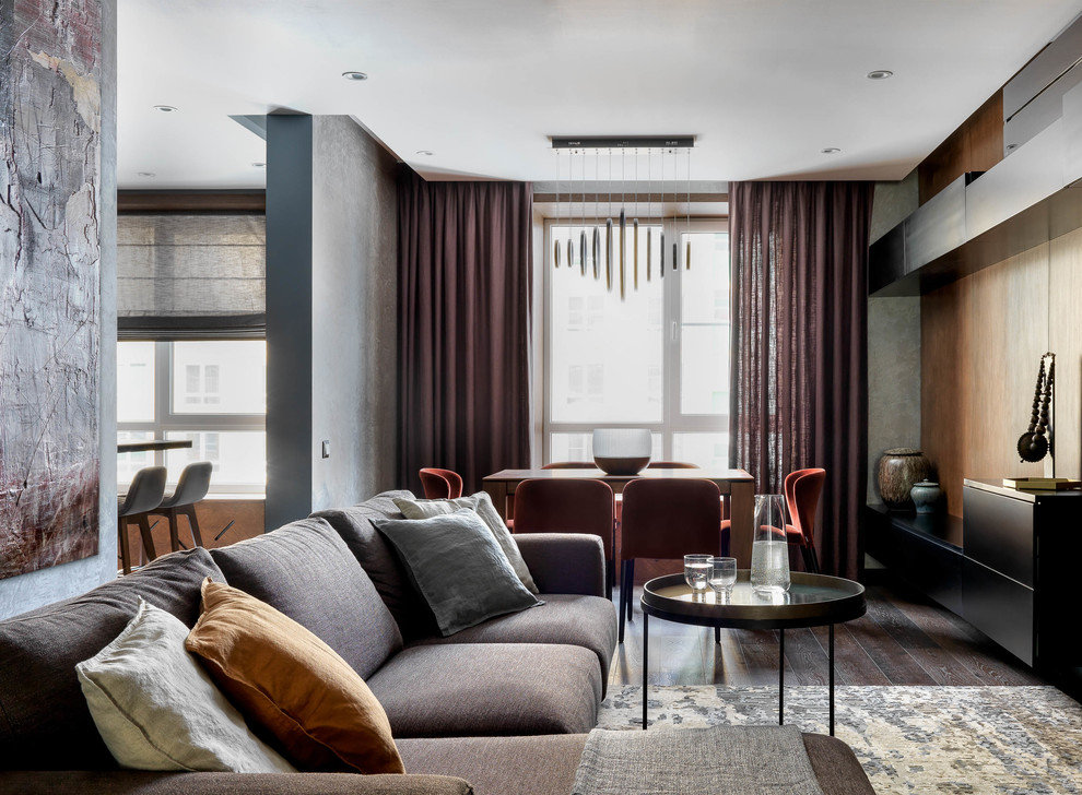 Пример оригинального дизайна: изолированная гостиная комната среднего размера в современном стиле с серыми стенами, темным паркетным полом, телевизором на стене и коричневым полом