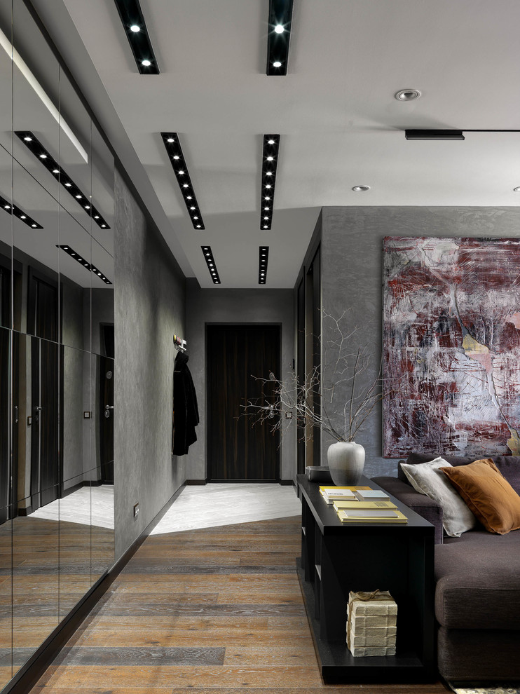 Источник вдохновения для домашнего уюта: изолированная, объединенная гостиная комната среднего размера в современном стиле с серыми стенами, темным паркетным полом, телевизором на стене и коричневым полом