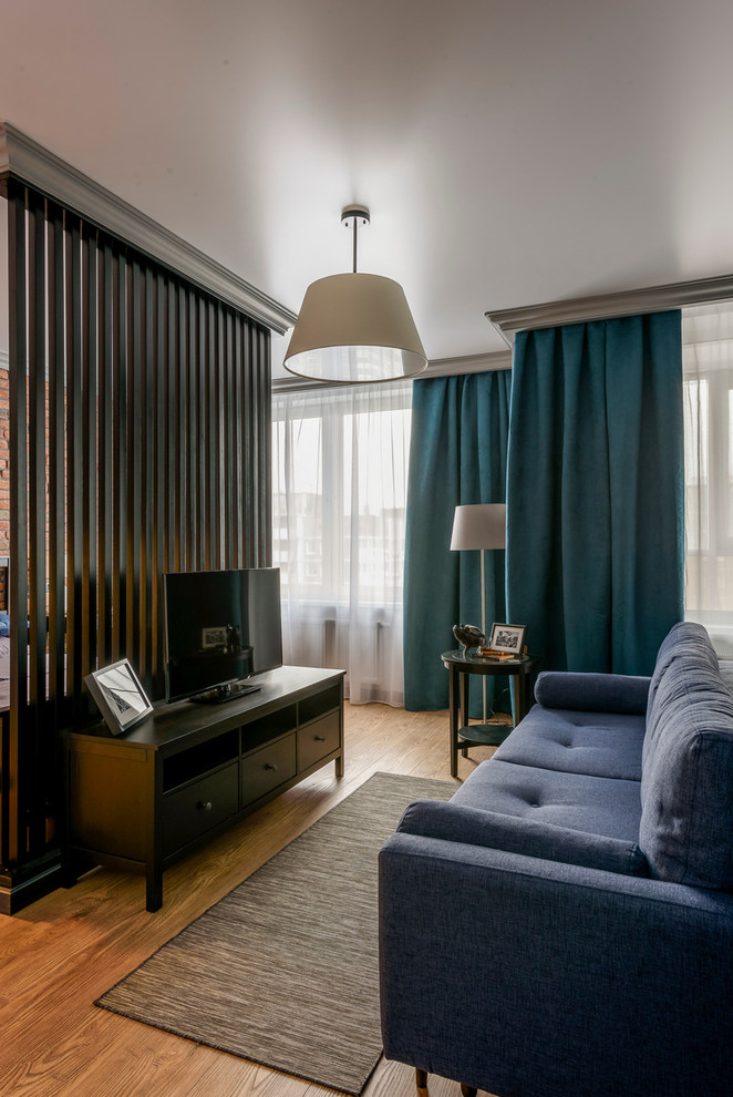 Modelo de salón tipo loft urbano pequeño con paredes grises, suelo de madera en tonos medios y televisor independiente
