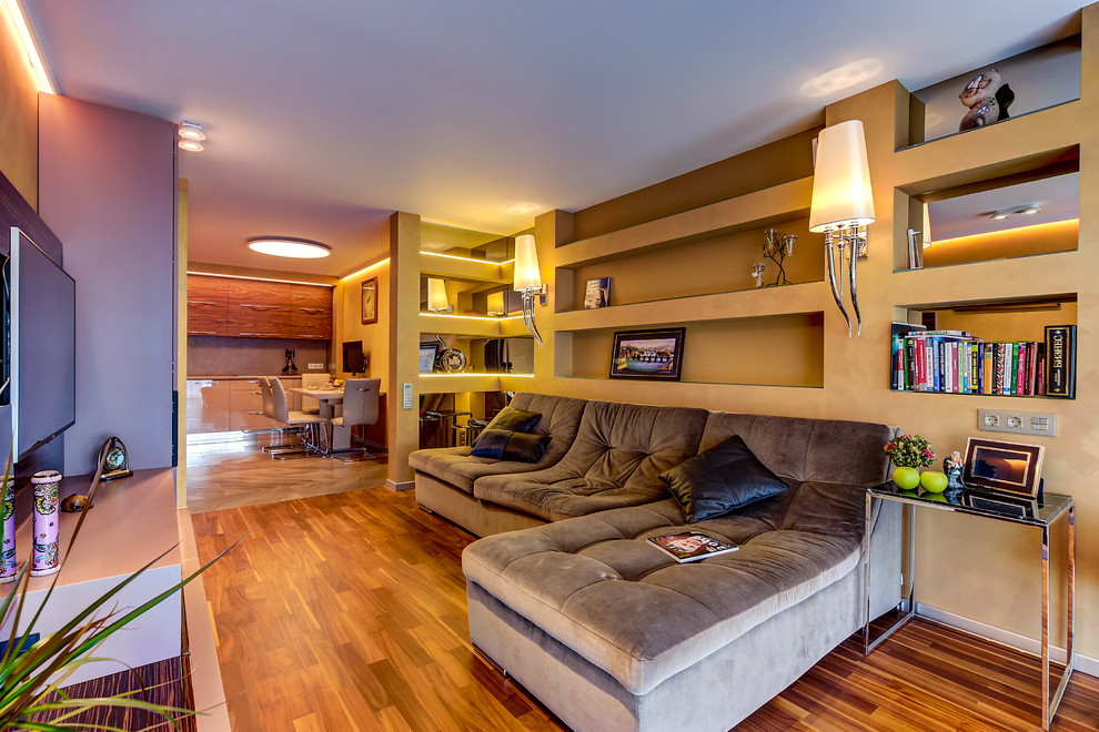 На фото: открытая гостиная комната среднего размера в современном стиле с желтыми стенами, темным паркетным полом, стандартным камином, отдельно стоящим телевизором, коричневым полом и тюлем на окнах с