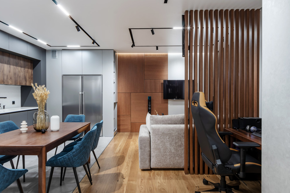 Imagen de salón abierto contemporáneo extra grande sin chimenea con paredes grises, suelo de madera en tonos medios y televisor colgado en la pared