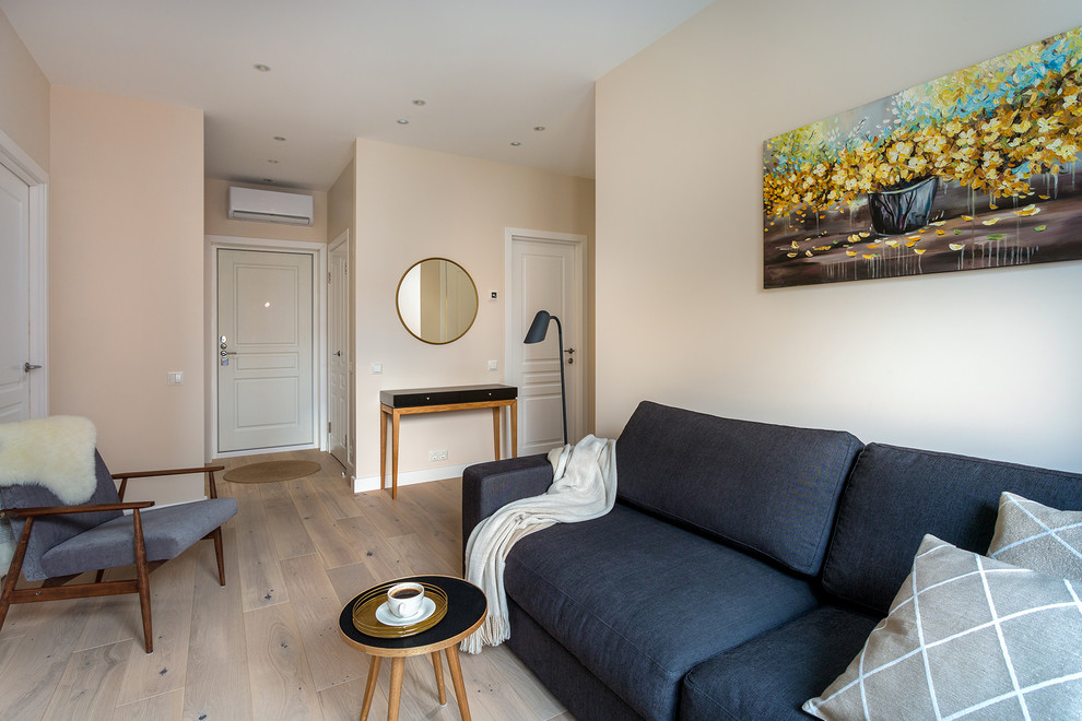 На фото: открытая гостиная комната среднего размера в скандинавском стиле с бежевыми стенами, светлым паркетным полом, телевизором на стене и бежевым полом