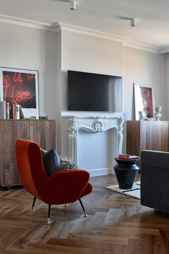 Foto di un soggiorno bohémian con pareti grigie, pavimento in legno massello medio, camino classico e TV a parete
