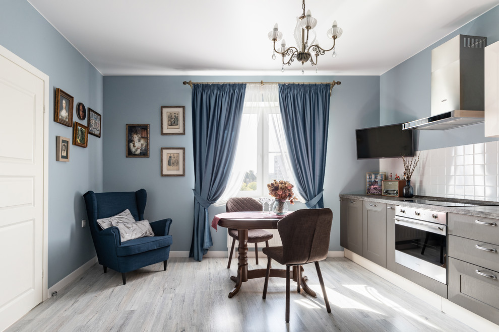 На фото: изолированная гостиная комната в стиле неоклассика (современная классика) с с книжными шкафами и полками, синими стенами, полом из ламината, телевизором на стене и серым полом с