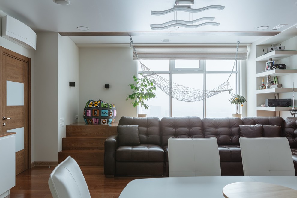 Diseño de salón escandinavo grande con paredes blancas, suelo de madera en tonos medios y televisor colgado en la pared