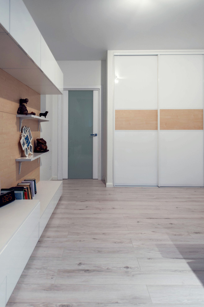 Modern inredning av ett litet separat vardagsrum, med vita väggar, laminatgolv och en fristående TV