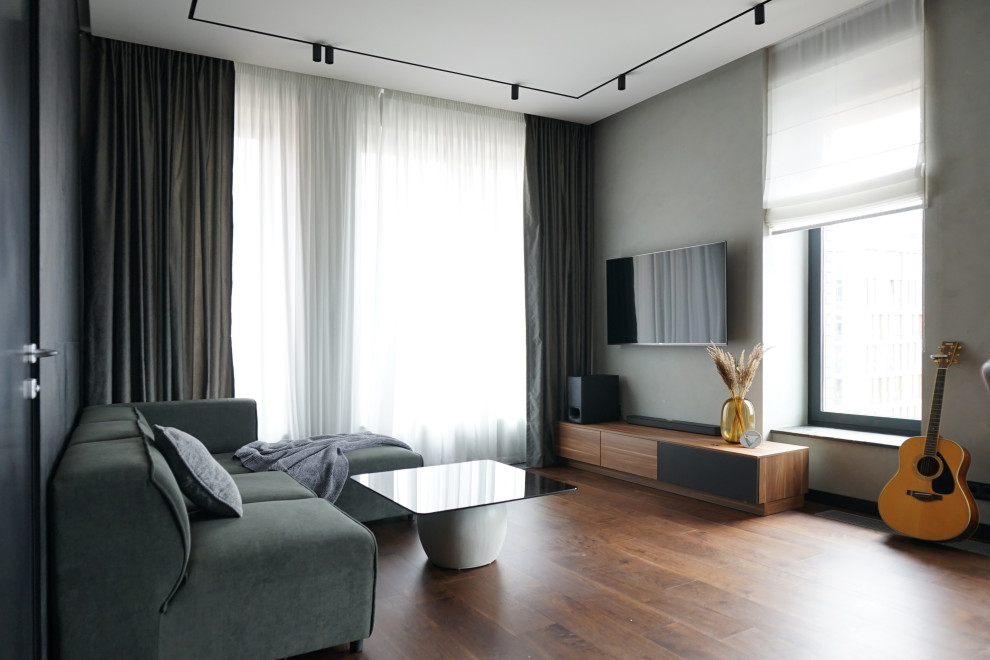 Cette image montre un salon design de taille moyenne et ouvert avec un mur gris, un sol en bois brun et un téléviseur fixé au mur.