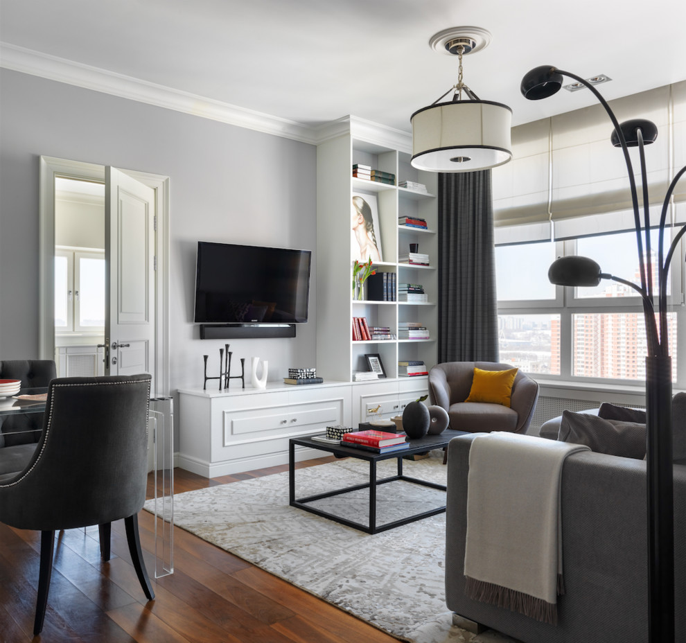 На фото: объединенная гостиная комната в стиле неоклассика (современная классика) с серыми стенами, паркетным полом среднего тона, телевизором на стене и коричневым полом с