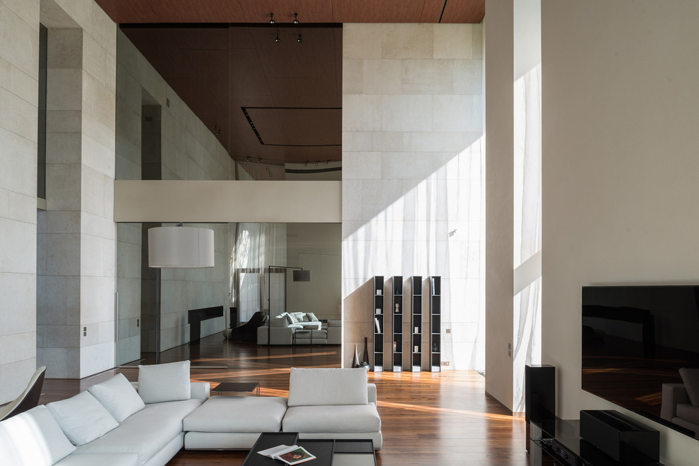 Réalisation d'une salle de séjour design ouverte avec un mur beige, un sol en bois brun et un téléviseur fixé au mur.