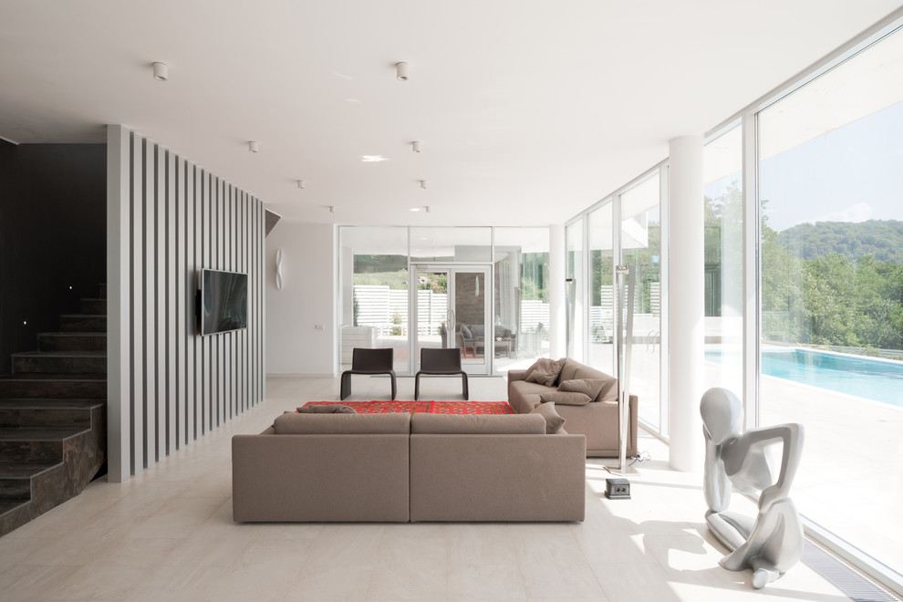 Пример оригинального дизайна: парадная, открытая гостиная комната в современном стиле с белыми стенами, телевизором на стене и светлым паркетным полом без камина