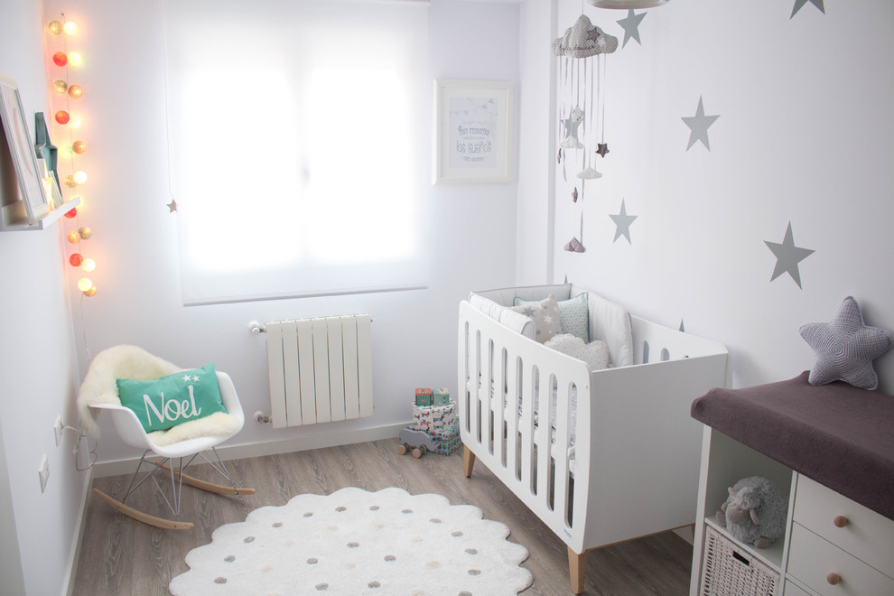 Foto de habitación de bebé neutra nórdica pequeña con paredes blancas y suelo de madera en tonos medios
