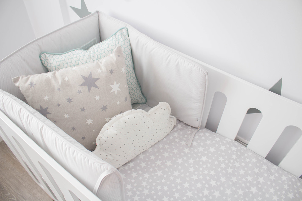 Ejemplo de habitación de bebé neutra nórdica pequeña con paredes blancas y suelo de madera en tonos medios