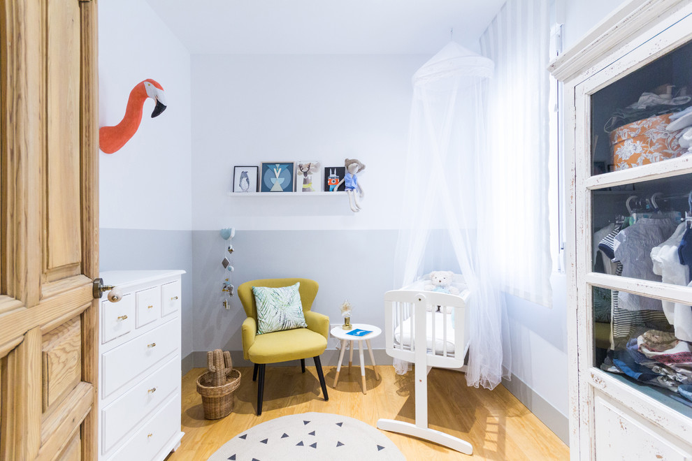 Imagen de habitación de bebé neutra ecléctica pequeña con paredes multicolor, suelo de madera en tonos medios y suelo marrón