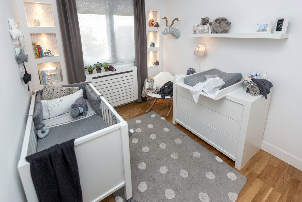 Mittelgroßes, Neutrales Skandinavisches Babyzimmer mit weißer Wandfarbe und braunem Holzboden in Madrid