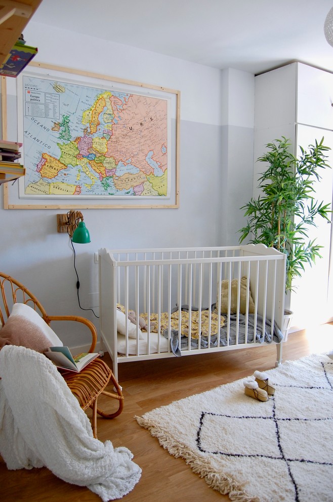 Diseño de habitación de bebé neutra escandinava pequeña con paredes grises y suelo laminado