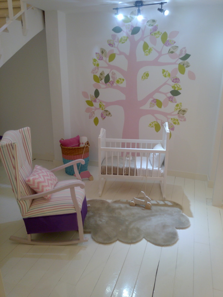 Esempio di una piccola cameretta per neonata classica con pareti bianche e pavimento in legno verniciato