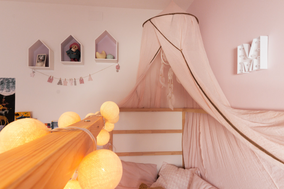 Diseño de habitación de bebé neutra contemporánea pequeña con paredes rosas, suelo laminado y suelo marrón