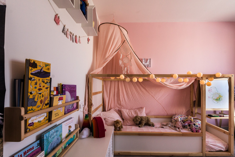 Photo of a small contemporary gender neutral nursery in Barcelona with pink walls, laminate floors and brown floors.