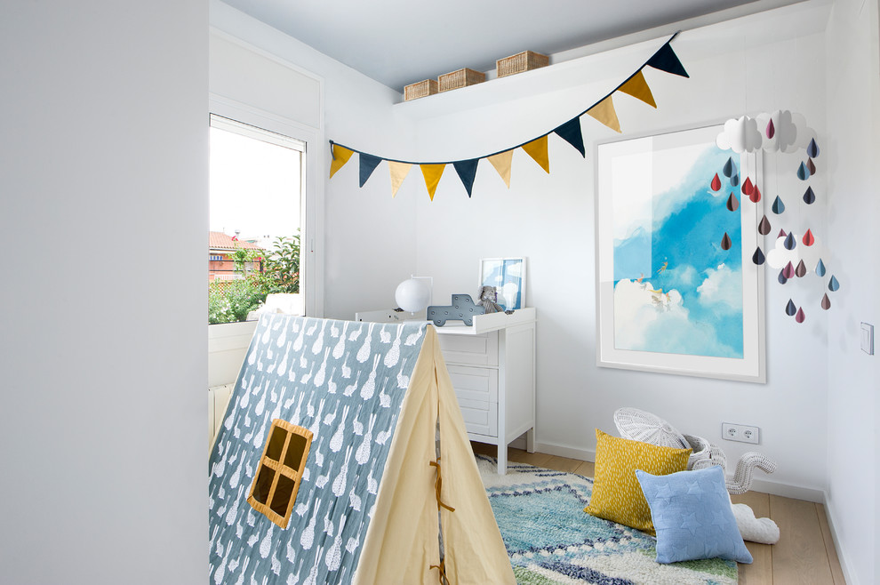 Exemple d'une chambre de bébé neutre scandinave de taille moyenne avec un mur blanc, un sol en bois brun et un sol marron.