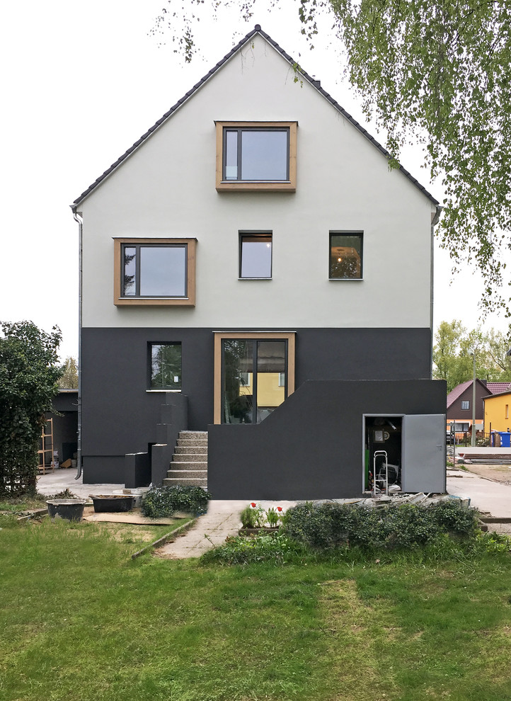 Medium sized and white contemporary two floor render detached house in Berlin with a pitched roof and a tiled roof.