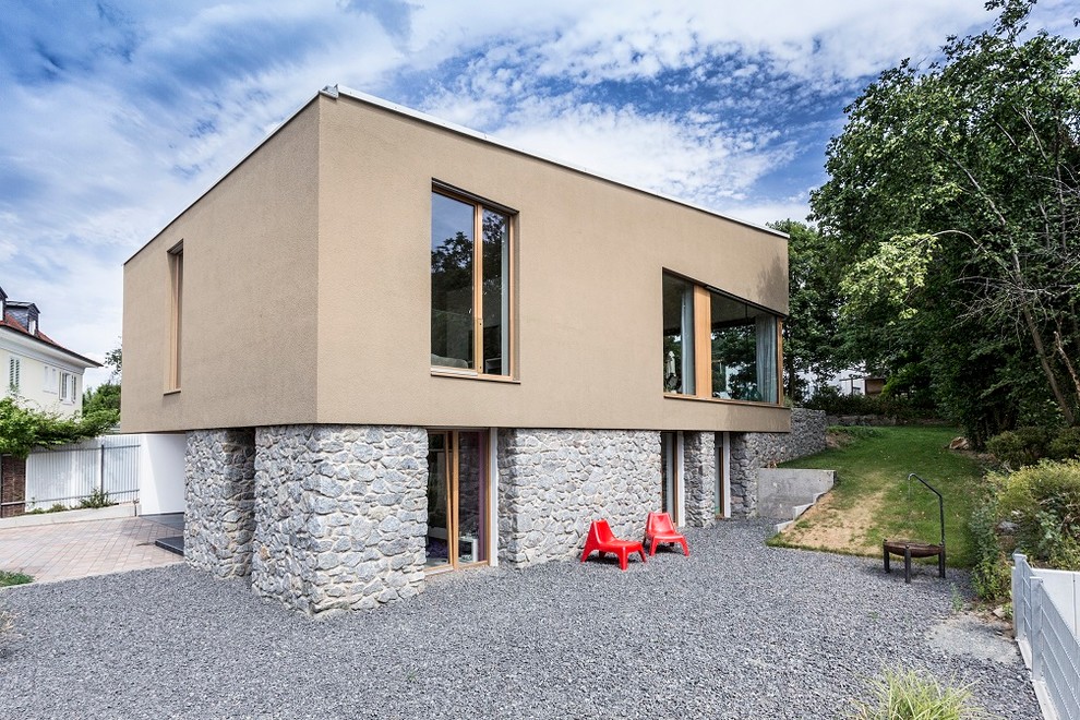 Modelo de fachada de casa beige contemporánea de tamaño medio de dos plantas con revestimientos combinados y tejado de un solo tendido