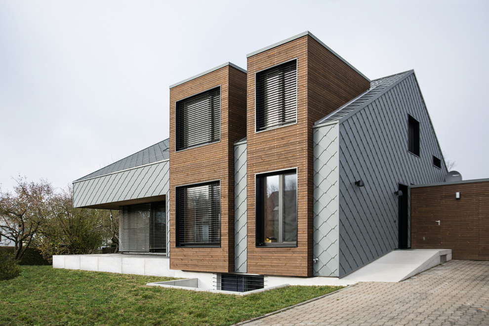 Cette photo montre une façade de maison métallique et grise moderne de taille moyenne et à un étage avec un toit à deux pans et un toit en métal.