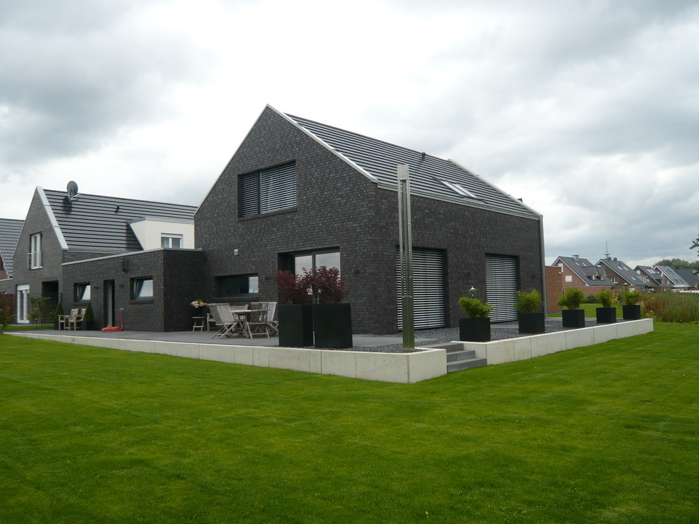 Großes, Zweistöckiges Modernes Einfamilienhaus mit Backsteinfassade, grauer Fassadenfarbe, Satteldach und Ziegeldach in Sonstige