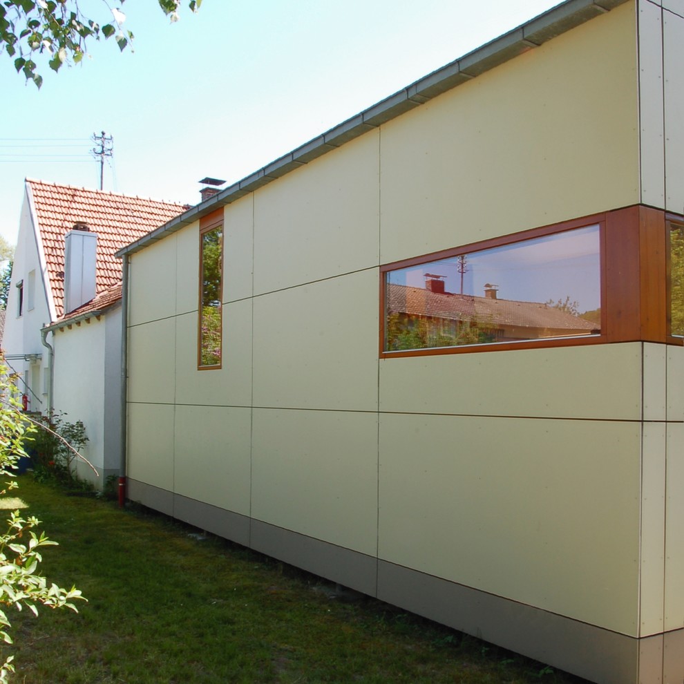 Idée de décoration pour un petite façade d'immeuble design en panneau de béton fibré avec un toit à deux pans et un toit en tuile.