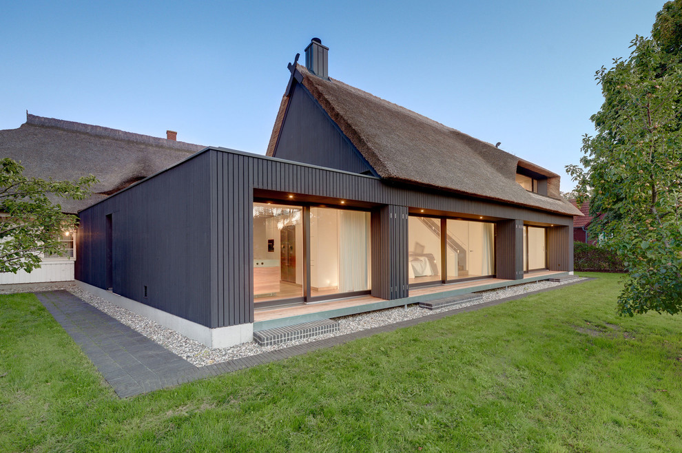 На фото: двухэтажный, деревянный, черный дом среднего размера в современном стиле с двускатной крышей с