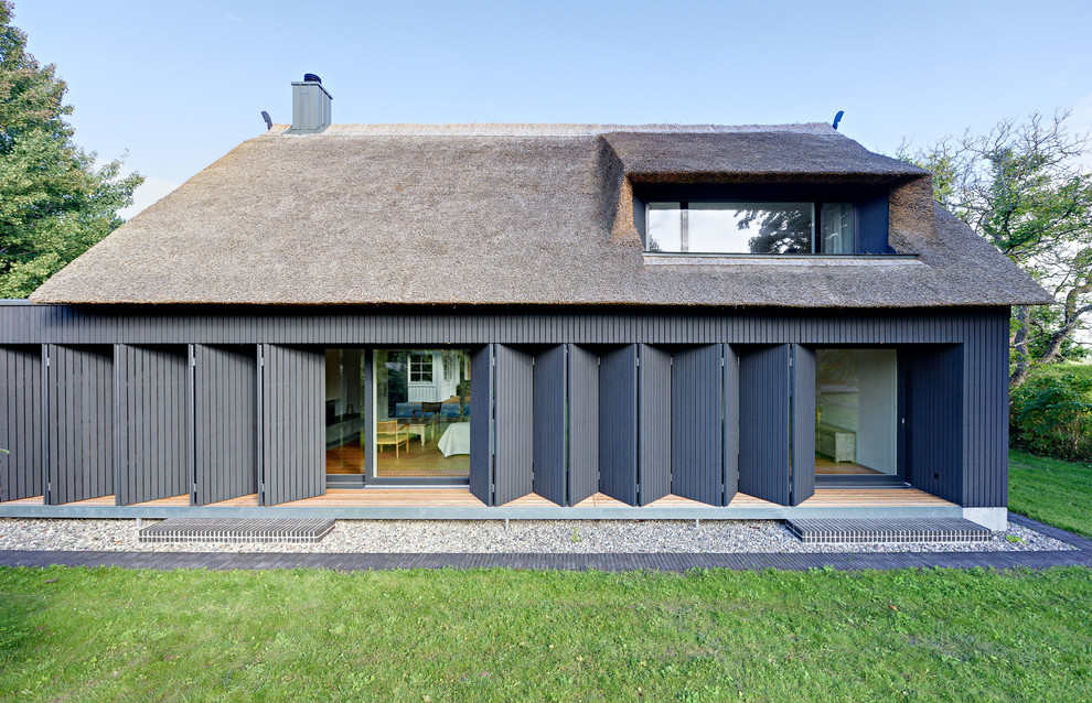 Modelo de fachada negra contemporánea de tamaño medio de dos plantas con revestimiento de madera y tejado a dos aguas