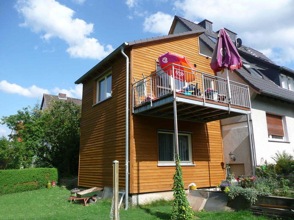 Aménagement d'une façade de maison marron contemporaine en bois à un étage avec un toit en appentis et un toit en tuile.