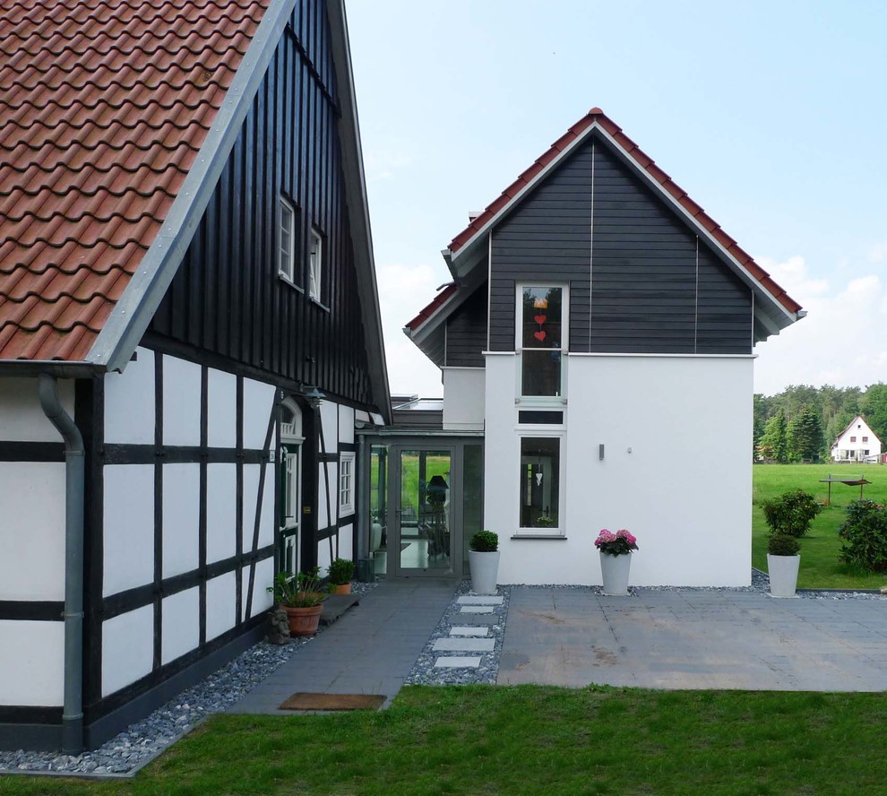 Diseño de fachada de casa blanca escandinava grande a niveles con revestimientos combinados, tejado a dos aguas y tejado de teja de barro