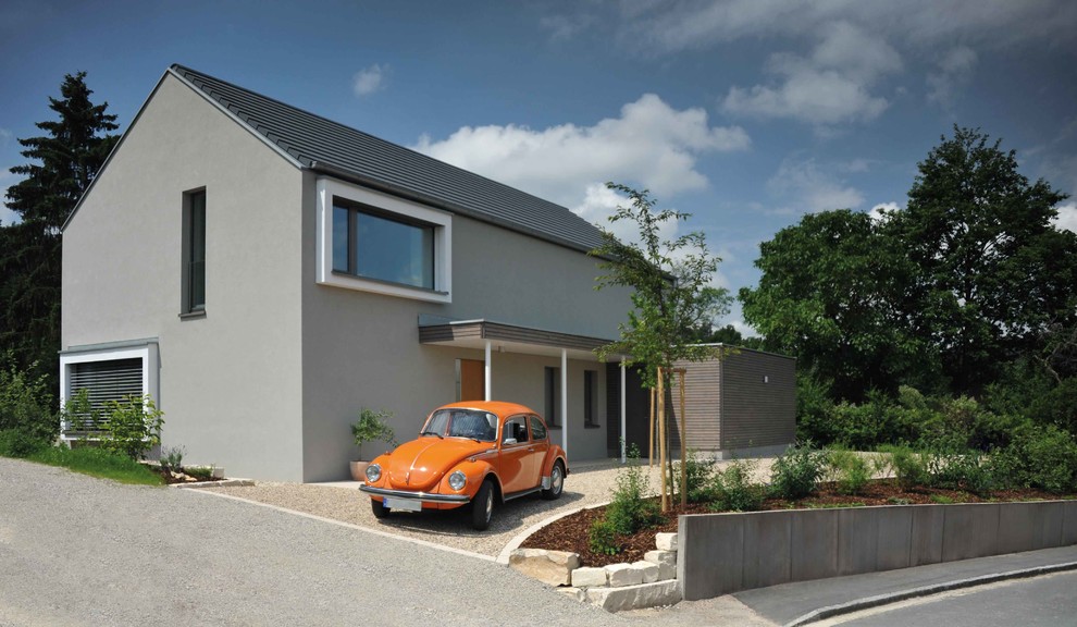 Imagen de fachada de casa gris minimalista de tamaño medio de dos plantas con revestimiento de estuco, tejado a dos aguas y tejado de teja de barro
