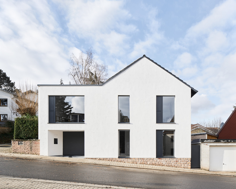 Modelo de fachada de casa blanca minimalista de tamaño medio de dos plantas con revestimiento de estuco, tejado a dos aguas y tejado de teja de barro