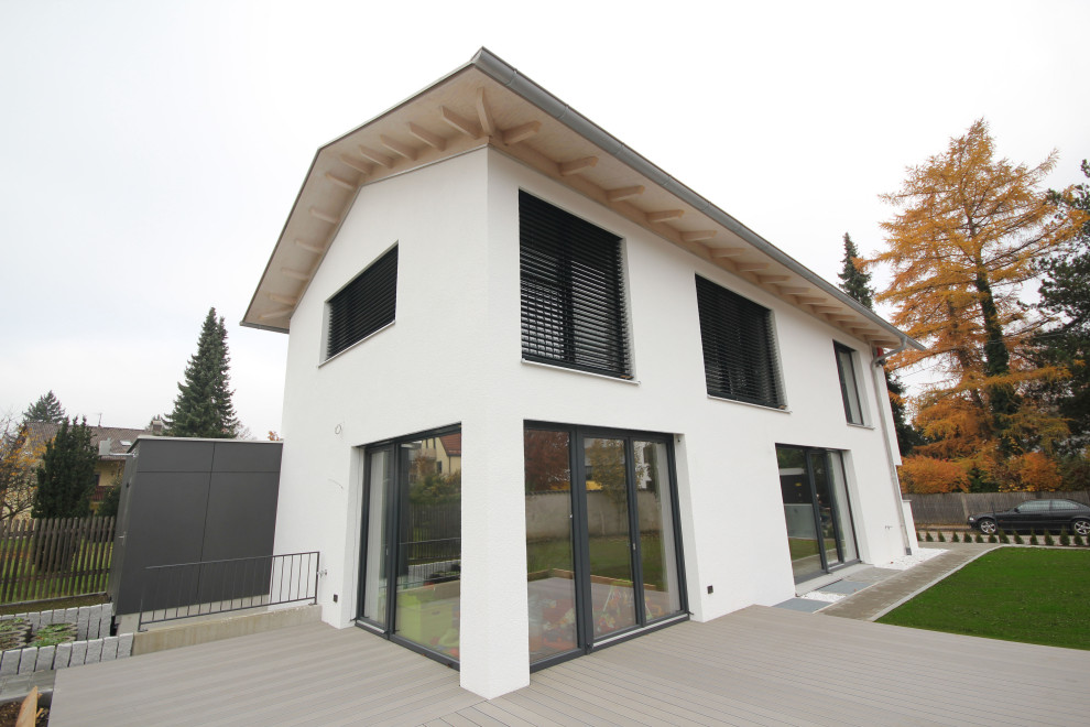 Mittelgroßes Modernes Einfamilienhaus mit Putzfassade, weißer Fassadenfarbe, Satteldach und Ziegeldach in München