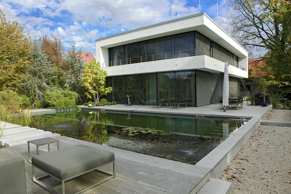 White and large contemporary two floor glass house exterior in Munich with a flat roof.