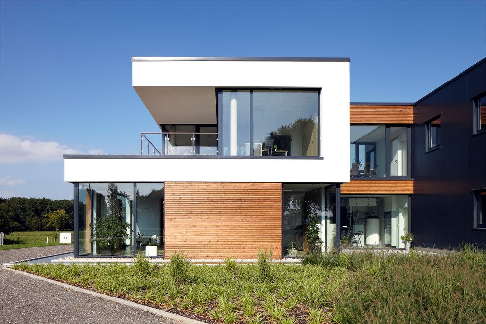 Exemple d'une façade de maison blanche tendance à un étage avec un toit plat et un revêtement mixte.