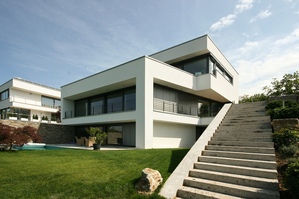 Modelo de fachada blanca minimalista grande a niveles con revestimientos combinados y tejado plano
