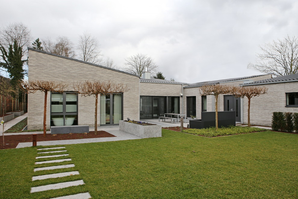 Идея дизайна: одноэтажный, большой, серый частный загородный дом в стиле модернизм с облицовкой из камня, односкатной крышей и черепичной крышей