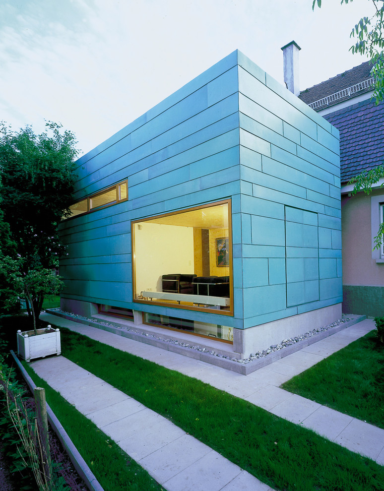 Cette image montre une petite façade de maison bleue design de plain-pied avec un toit plat.