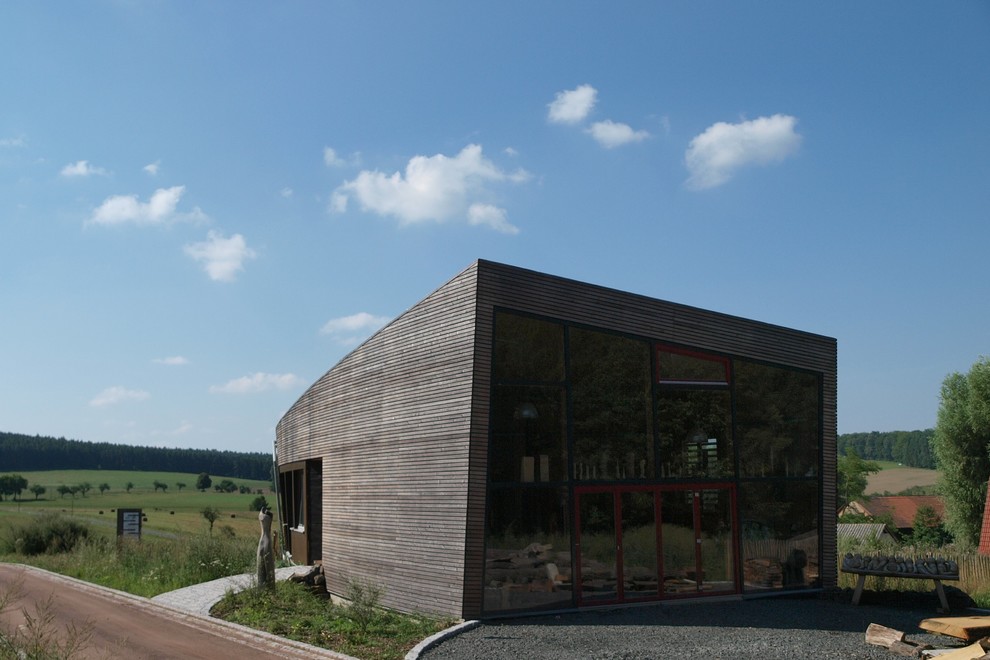 Imagen de fachada de casa marrón contemporánea grande de una planta con revestimiento de madera, tejado plano y techo verde
